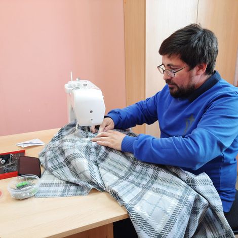 Батюшка Константин скоро работает за швейной машиной, умело управляясь с большими изделиями.